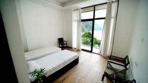 a white bedroom with a bed and a large window at Phool Chatti Yoga Ashram 7 day Yoga Retreat in Shivpuri +4 photos