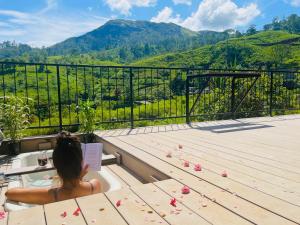 a woman sitting in a bath tub on a balcony with mountains at 007Dickoya in Dikoya