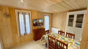 Un comedor con mesa y sillas y un televisor. en Les Myrtilles Le Mont Dore 6pers, en Le Mont-Dore