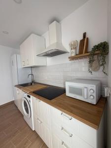 a kitchen with white cabinets and a microwave at Vv Estudio88 in Valverde