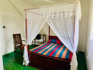 a bedroom with a canopy bed and a chair at Last Will Hill Top House in Weligama