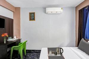 ノイダにあるHotel Eros Estateのベッドとテーブルと緑の椅子があるホテルの部屋