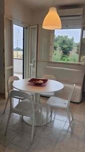 Una mesa y sillas blancas en una habitación con ventana. en Diamante, en Torre Inserraglio