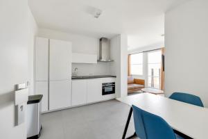 アウウドルプにあるAppartement Aloha 4P - Residence Kabbelaarsbankの白いキッチン(テーブル、青い椅子付)