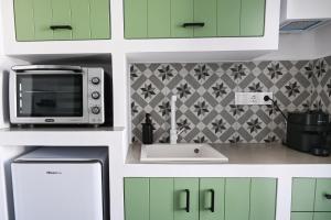a kitchen with green cabinets and a microwave at The Friend's House Milos in Triovasálos