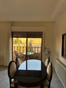 a dining room with a table and chairs and a balcony at Furnished Family Apartment in Dahyet Al-Rasheed in Amman