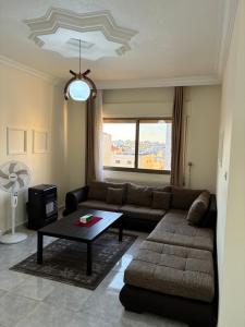 a living room with a couch and a table at Furnished Family Apartment in Dahyet Al-Rasheed in Amman