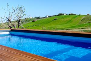 a pool of blue water with a hill in the background at Villa Ophite in Offida