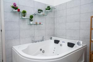 a white bath tub in a bathroom with plants at Dimora Cavallo a 150m da spiaggia sabbiosa in Torre Santa Sabina