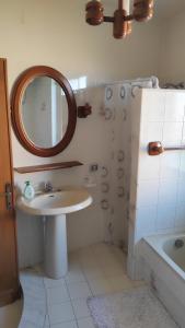 a bathroom with a sink and a mirror and a tub at Cora Manna casa vacanze in Càbras