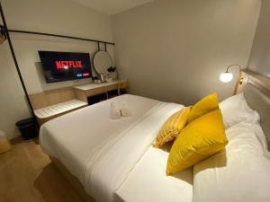 a bedroom with a bed with yellow pillows and a tv at 32E Home Sleep Home in Kuah
