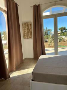 a bedroom with a bed and a large glass door at Villa Rebecca in Porto Cesareo