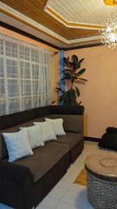 a living room with a brown couch with pillows at KBC ZAI Baguio Staycation 1 in Baguio