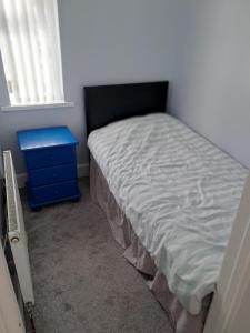 a small bedroom with a bed and a blue nightstand at Entire House in Belfast