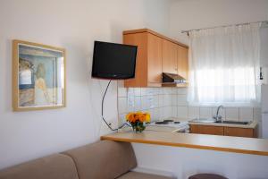a kitchen with a counter with a tv on the wall at Stefanie Studios in Egina