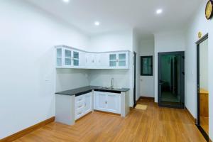 an empty kitchen with white cabinets and a sink at Hotel Phạm Gia Phan Thiết in Phan Thiet