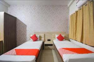 two beds in a small room with red pillows at Hotel Eden Park in Nimtita