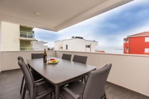 a table with chairs and a bottle of wine on a balcony at Apartman Luna in Trogir