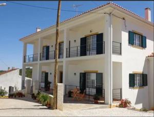 a white house with black windows and a balcony at Casa Das Estevas in Vila Velha de Ródão
