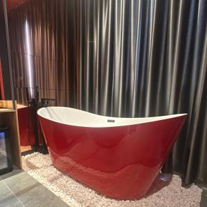 eine rot-weiße Badewanne vor einem Vorhang in der Unterkunft Couple Hotel - Khách Sạn Tình Yêu Hóc Môn in Ho-Chi-Minh-Stadt