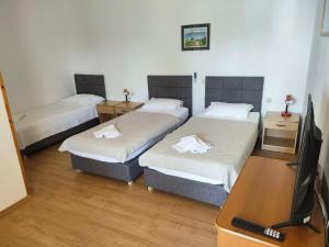 a room with three beds and a desk with a television at Tonino apartments in Pag