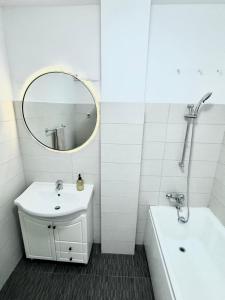 un bagno con un lavandino, uno specchio e una vasca di Clock House a Bucarest