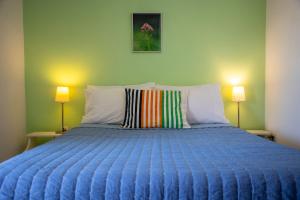 a bedroom with a blue bed with two lamps at Stefanie Studios in Egina