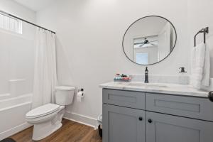 ein weißes Bad mit einem WC und einem Spiegel in der Unterkunft NEW Thibodeaux House Cajun Luxury 65 TV Fast WiFi in Lafayette + 26 Fotos