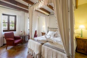 a bedroom with a canopy bed and a chair at Son Sant Jordi in Pollença