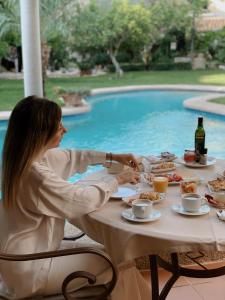 a woman sitting at a table with food in front of a pool at Son Sant Jordi in Pollença