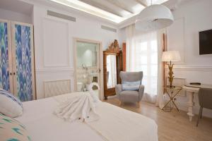 a white bedroom with a bed and a chair at Son Sant Jordi in Pollença