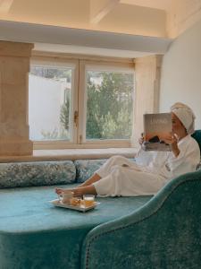 a woman sitting on a couch reading a book at Son Sant Jordi in Pollença