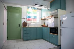 a kitchen with blue cabinets and a green door at Stefanie Studios in Egina