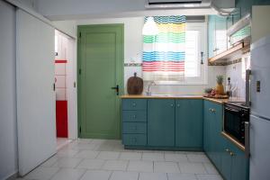 a kitchen with blue cabinets and a green door at Stefanie Studios in Egina