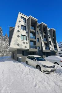 un coche aparcado frente a un edificio en la nieve en Pine Forest Magic, en Bjelašnica