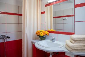 a bathroom with a sink and a mirror and flowers at Stefanie Studios in Egina