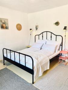 a bedroom with a black bed with white sheets and a pink chair at Bánhiday J70 Beach House in Balatonvilágos