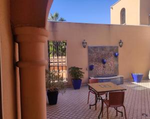 un patio avec une table, des chaises et une cheminée dans l'établissement Chambre Zagora, Riad 8 au village naturiste Couple only, au Cap d'Agde