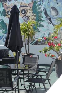 a table with chairs and an umbrella in front of a mural at Calma Chicha Rooms in Playa del Carmen
