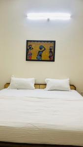 a bed with two pillows and a painting on the wall at Hotel Laxman Ganga in Rishīkesh
