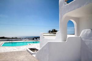 une villa blanche avec une piscine et un ciel bleu dans l'établissement The Fisherman's House Santorini, à Akrotiri