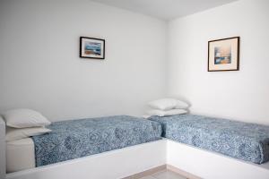 two beds in a room with white walls at Stefanie Studios in Egina
