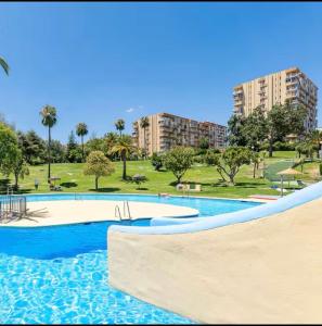 a swimming pool in a park with trees and buildings at Apartamento JÚPITER Vistas in Benalmádena