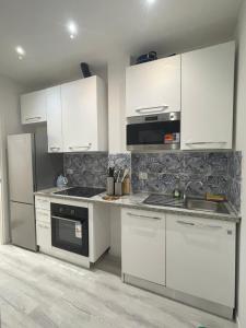 a kitchen with white cabinets and a stove top oven at Muzien B&B in Imola