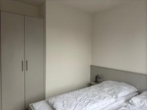 a white bedroom with a bed and a cabinet at FeWo Clara - Ferienhaus Hiddensee in Kloster