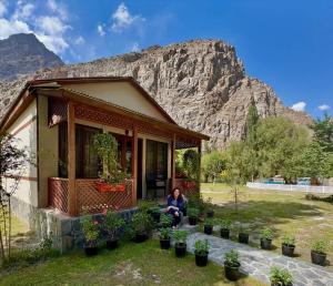a woman sitting outside of a house with plants at Dream Nest Resorts in Skardu