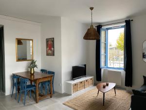 a living room with a table and a television at Jules Appart'Hotel, Appartements Centre Ville Romans sur Isère in Romans-sur-Isère