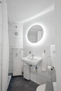 een witte badkamer met een wastafel en een spiegel bij Modernes Studio im Erdgeschoss - ZachaStay Koblenz Guels in Koblenz