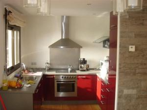 cocina con armarios rojos y fogones en VILLA SOL Y MAR - Modern luxury with pool y sea view, en Lloret de Mar