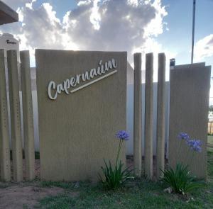 a sign in front of a fence with purple flowers at Departamentos Capernaum in Santa Rosa